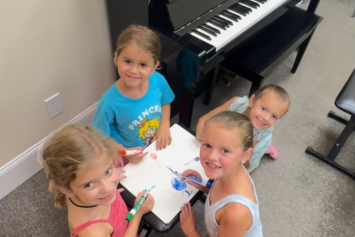 Four students looking at camera during a group piano class.