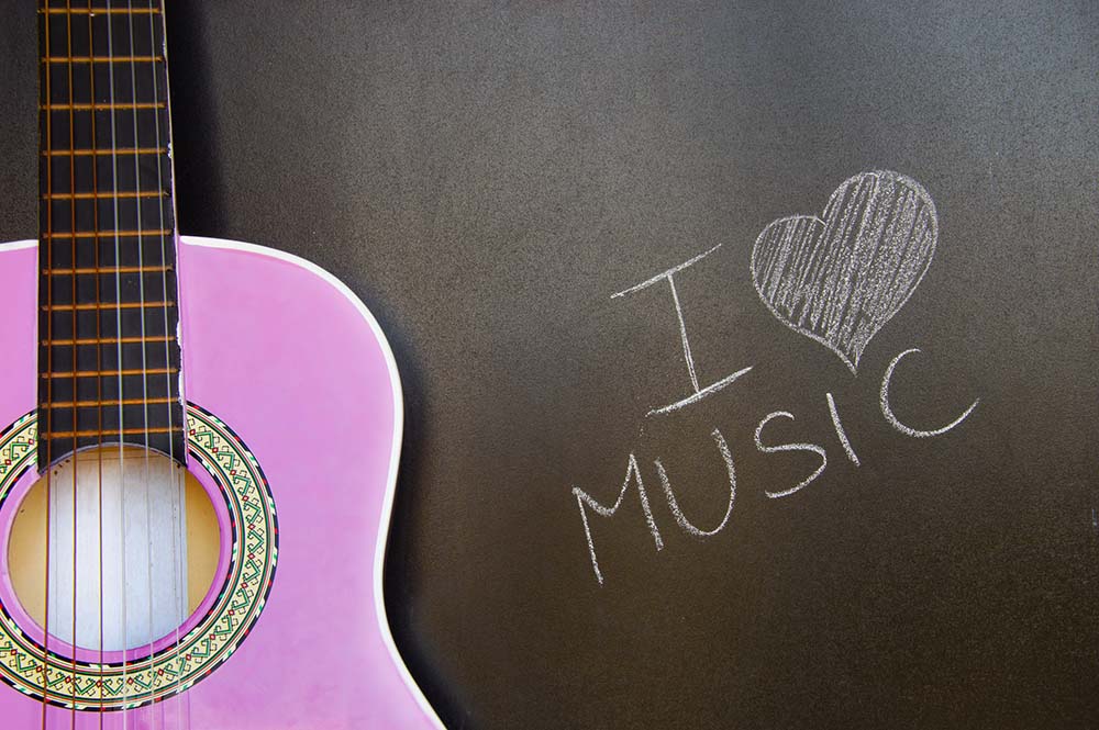 Pink guitar with I love music written on a chalkboard